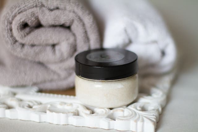 A jar of Epsom salt on a tray with towels ready to be used for a salt bath that is beneficial for health and beauty.