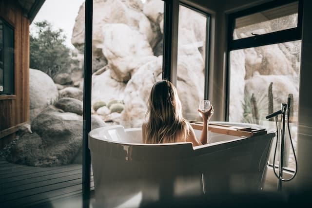 A woman drinking wine in a salt bath and relaxing.