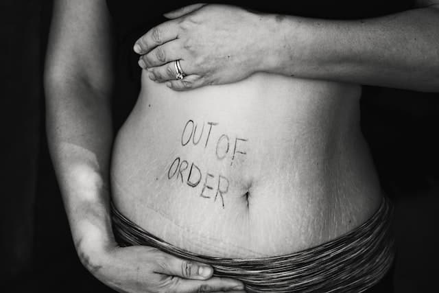 Person showing their belly with "out of order" written on it